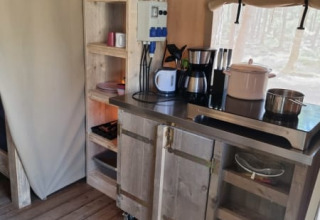 Küchenecke im Safarizelt auf Camping het Horstmannsbos in den Niederlanden mit Holzregalen und Geräten.