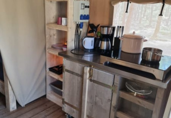 Køkkenhjørne i en safaritelt på Camping het Horstmannsbos i Holland med træmøbler og køkkenudstyr.