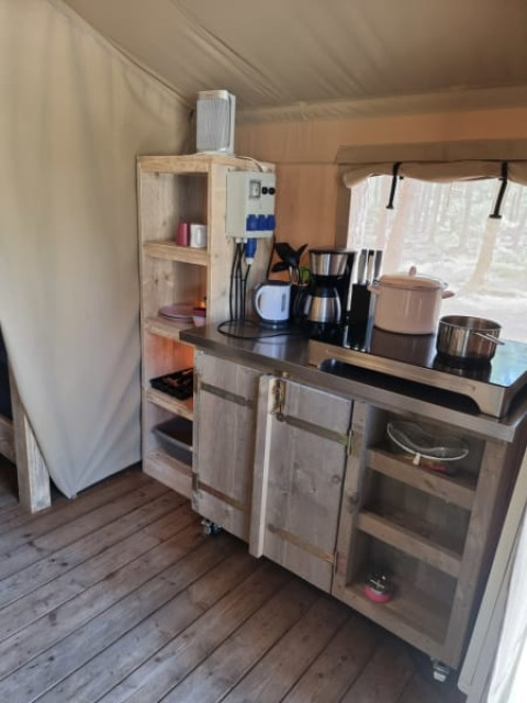 Køkkenhjørne i en safaritelt på Camping het Horstmannsbos i Holland med træmøbler og køkkenudstyr.