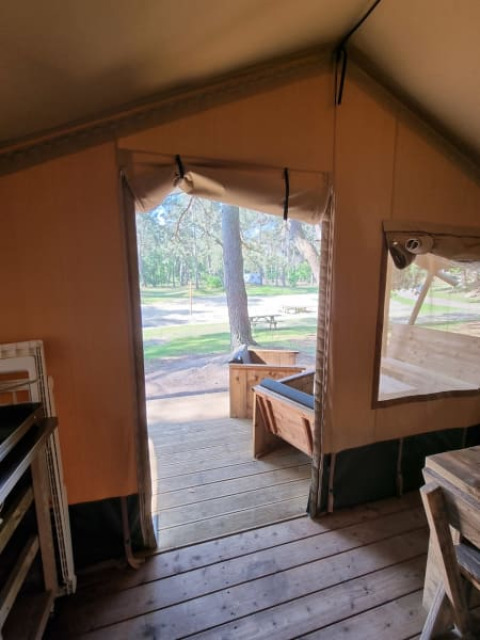 Vista desde el interior de una tienda safari en Camping het Horstmannsbos, Países Bajos, con plataforma de madera.
