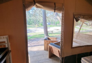 Vista desde el interior de una tienda safari en Camping het Horstmannsbos, Países Bajos, con plataforma de madera.
