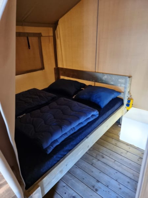 Vista interior de una tienda safari con cama doble en Camping het Horstmannsbos, Países Bajos.