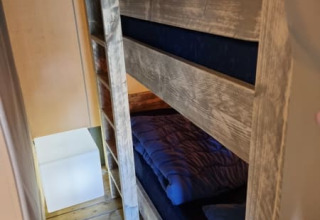 Letti a castello in una tenda safari al Camping het Horstmannsbos nei Paesi Bassi, legno e biancheria blu.