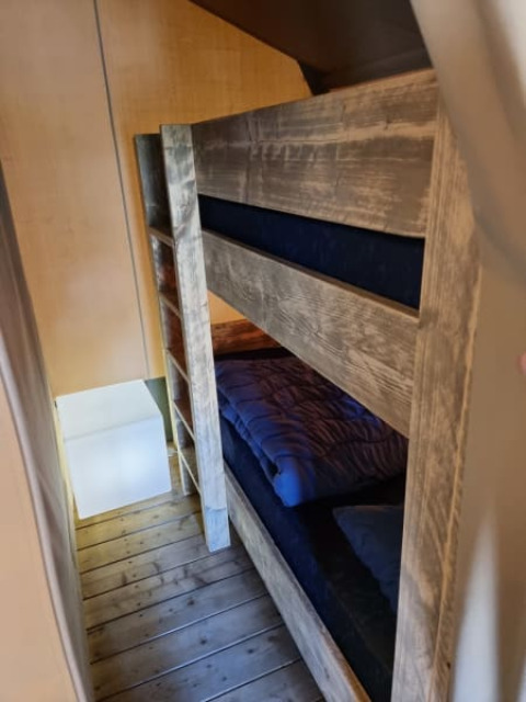 Stapelbedden in een safaritent bij Camping het Horstmannsbos, Nederland, houten planken en blauw beddengoed.