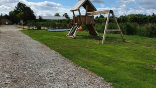 Parco giochi e sentiero di ghiaia presso la tenda Safari al Camping de Oude Rijn nei Paesi Bassi sotto cielo nuvoloso.