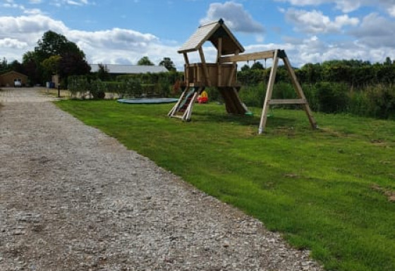 Parco giochi e sentiero di ghiaia presso la tenda Safari al Camping de Oude Rijn nei Paesi Bassi sotto cielo nuvoloso.