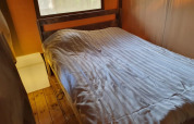 Vista interior de una tienda safari en Camping Elbeling, Alemania, con una cómoda cama y suelo de madera.