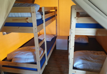 Interno della tenda safari al Ballum Camping in Danimarca con due letti a castello e pavimento in legno.