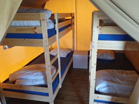 Interior of safari tent at Ballum Camping in Denmark, featuring two bunk beds and wood flooring.