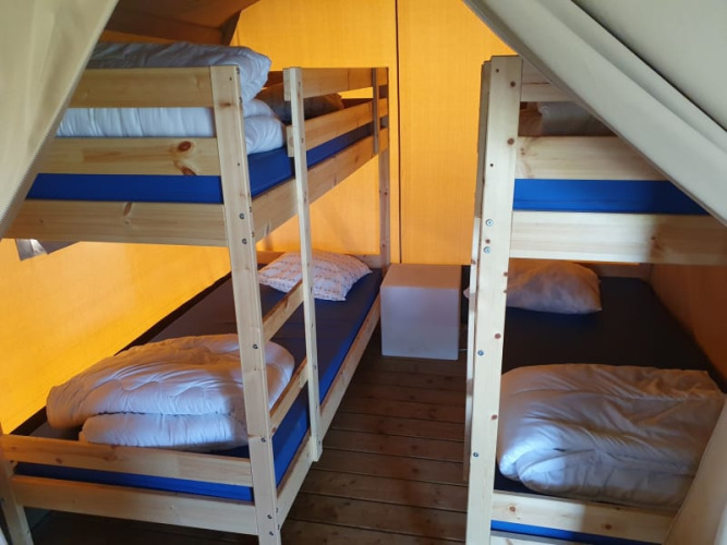 Interior de una tienda safari en Ballum Camping, Dinamarca, con dos literas y suelo de madera.