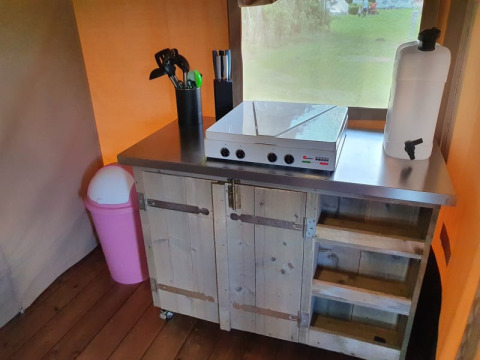 Lille køkken i safaritelten på Camping la Cour d'Enchère med kogeplade, redskaber og affaldsspand.