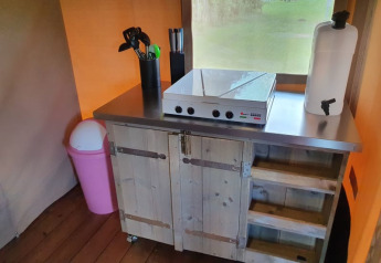 Angolo cucina compatto nella tenda safari presso Camping la Cour d'Enchère in Francia, con fornello e utensili.