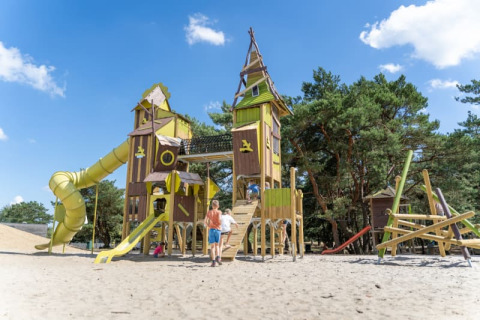 Niños juegan en un gran parque infantil con torres y toboganes en Safari tent, Camping GT Keiheuvel, Bélgica.