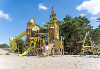 Bambini giocano in un grande parco giochi con torri e scivoli presso Safari tent, Camping GT Keiheuvel, Belgio.