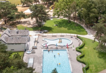 Vista aerea di piscina e area giochi tra alberi al Safari tent del Camping GT Keiheuvel in Belgio.