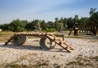 Parco giochi sabbioso vicino a una tenda safari al Camping GT Keiheuvel in Belgio, con strutture da arrampicata.