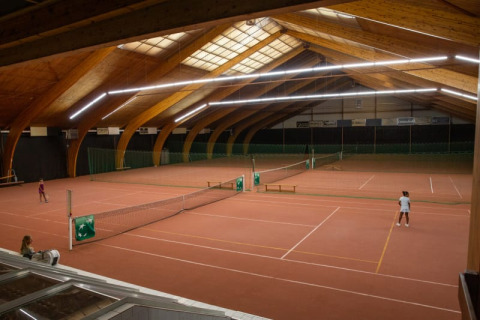 Cancha de tenis cubierta estilo tienda safari en Camping GT Keiheuvel, Bélgica, con jugadores en acción.