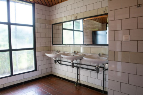 Baño moderno en Camping GT Keiheuvel, Bélgica, con tres lavabos, gran espejo y ventanas grandes.