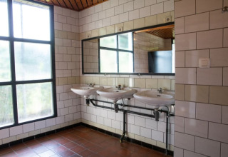 Baño moderno en Camping GT Keiheuvel, Bélgica, con tres lavabos, gran espejo y ventanas grandes.