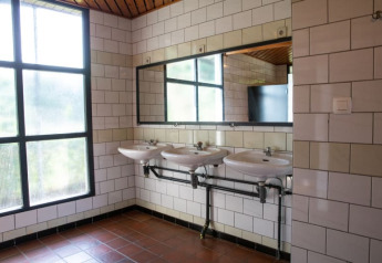 Bagno moderno con tre lavandini, grande specchio e finestre al Camping GT Keiheuvel in Belgio.