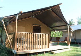 Safari tent with private deck and sanitary facilities, set in greenery for a comfortable glamping stay.