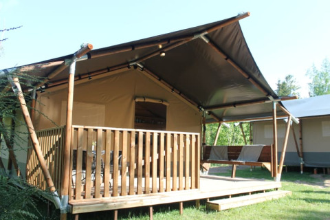 Tente safari avec terrasse privée et sanitaires, idéale pour un séjour glamping confortable en nature.