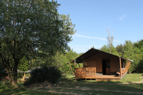 Safaritent met privé sanitair en veranda bij Tolne Camping in Denemarken, omgeven door bomen en groen.