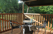 Zonnig houten terras met tafel en stoelen bij Safari tent + sanitair op Tolne Camping in Denemarken.