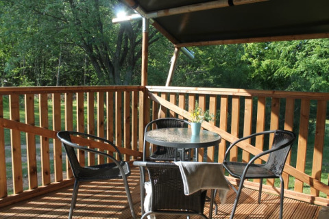 Sonnige Holzterrasse mit Tisch und Stühlen am Safari-Zelt mit Sanitär auf Tolne Camping, Dänemark.