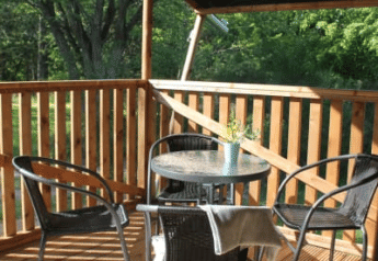 Terrazza coperta con tavolo e sedie del Safari tent + servizi igienici a Tolne Camping, Danimarca, vista sul verde.