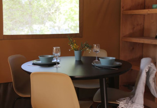Indretning i safari-telt på Tolne Camping, Danmark, med dækket spisebord og moderne stole.