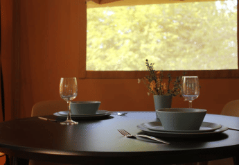 Table dressée pour deux dans une tente safari avec vue sur la nature à Tolne Camping, Danemark.