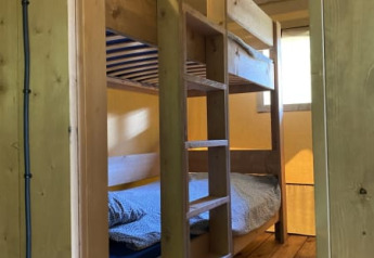 Houten stapelbed in een safaritent met sanitair bij Tolne Camping in Denemarken, gezien vanuit de deuropening.