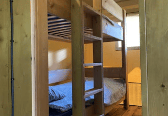 Holzetagenbett in einem Safarizelt mit Bad bei Tolne Camping in Dänemark, vom Eingang aus gesehen.