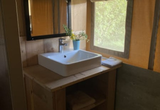 Wastafel met spiegel en handdoeken in een safaritent met sanitair op Tolne Camping in Denemarken.