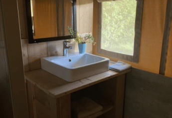 Vask med spejl og håndklæder i et safari telt med sanitære faciliteter på Tolne Camping i Danmark.