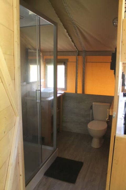 Badeværelse i safaritelt med bruser, toilet og vask på Tolne Camping i Danmark, set indefra teltet.