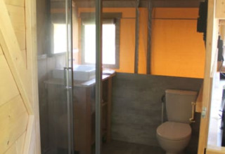 Badeværelse i safaritelt med bruser, toilet og vask på Tolne Camping i Danmark, set indefra teltet.