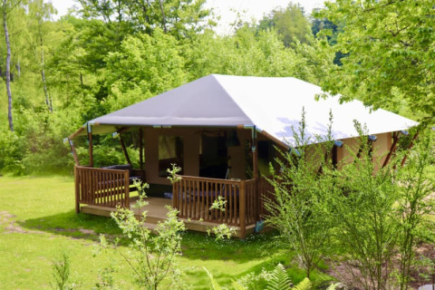 Safari glamping telt med terrasse og eget bad på Tolne Camping i Danmark, omgivet af grøn natur.