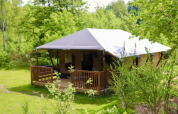 Tienda glamping tipo safari con baño privado en Tolne Camping, Dinamarca, rodeada de naturaleza verde.