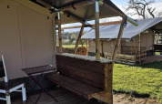 Tienda safari con terraza de madera y muebles sencillos en Minicamping MiO, Alemania, otras tiendas visibles.