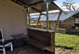 Tienda safari con terraza de madera y muebles sencillos en Minicamping MiO, Alemania, otras tiendas visibles.