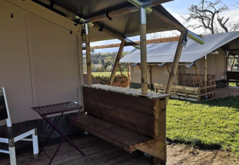 Safari telt med træterrasse og simple møbler på Minicamping MiO i Tyskland, udsigt til flere telte.