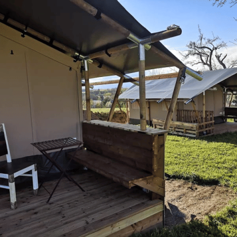 Safari tent with wooden deck and basic furniture at Minicamping MiO in Germany, view of other tents.