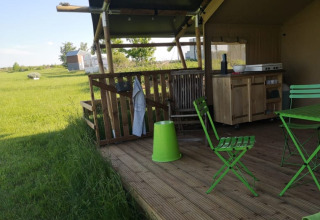 Outdoor deck of a safari tent at Minicamping MiO in Germany with green chairs and a scenic rural view.