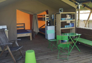 Tienda safari en Minicamping MiO en Alemania con sillas verdes, literas y área de estar abierta.