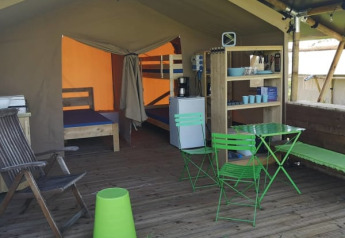 Tenda safari al Minicamping MiO in Germania con sedie verdi, letti a castello e area soggiorno aperta.