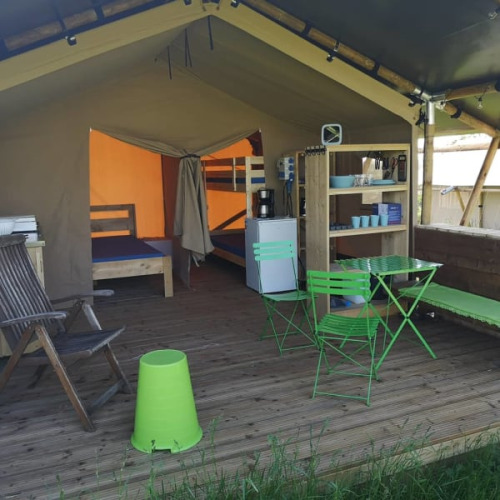 Safaritent bij Minicamping MiO in Duitsland met groene stoelen, stapelbedden en open zithoek.