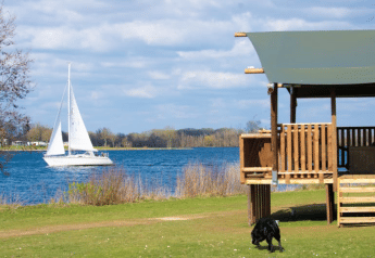 Safari-telt med sanitære faciliteter ved Recreatiepark Riverside i Holland, udsigt over sø og sejlbåd.