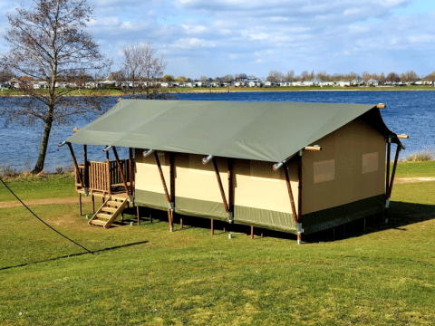 Tente safari avec sanitaires privés au bord de l'eau à Recreatiepark Riverside, Pays-Bas, sous le soleil.